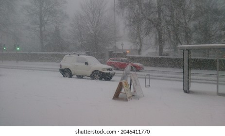 Snowing In UK Residential Town. Busy Road Full Of Snow With A Misty Background.