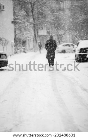 Snowing urban landscape with people passing by 