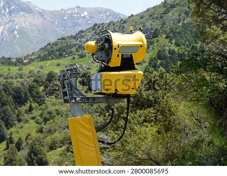 Snowmaking machine positioned in a mountain landscape. Equipment used for artificial snow production, ski resort maintenance and adaptation to changing winter conditions.