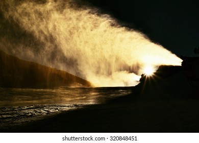 Snowmaking on slope. Skier near a snow cannon making fresch powder snow. Mountain ski resort and winter calm mountain landscape.  