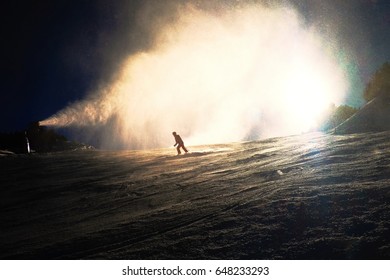 Snowmaking on slope. Skier near a snow cannon making fresch powder snow. Mountain ski resort and winter calm mountain landscape.  Winter specific