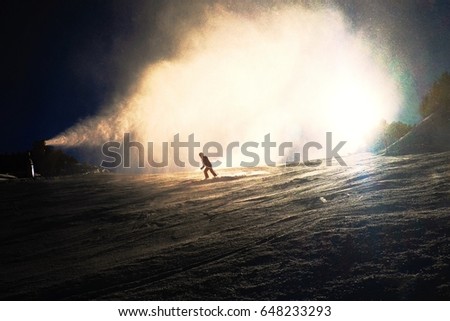 Snowmaking on slope. Skier near a snow cannon making fresch powder snow. Mountain ski resort and winter calm mountain landscape.  Winter specific