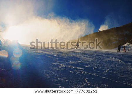Snowmaking on slope. Skier near a snow cannon making fresch powder snow. Mountain ski resort and winter calm mountain landscape.  