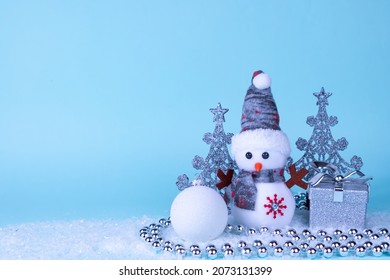 Snowman, gift, Christmas tree, Christmas ball on white snow on a blue background. Christmas New Year card. Place for an inscription