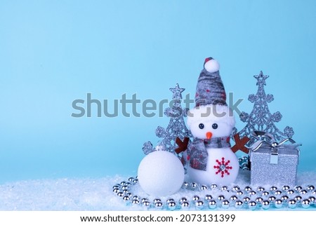 Snowman, gift, Christmas tree, Christmas ball on white snow on a blue background. Christmas New Year card. Place for an inscription