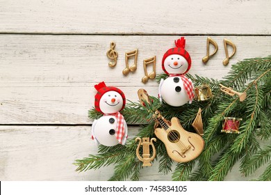 Snowman With Music Notes, Instruments On Christmas Tree Branch And Wooden Background 