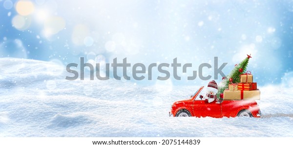 Snowman in Red car delivering christmas tree
and presents at winter snow
background.