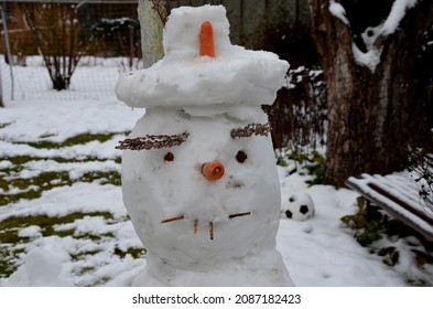 A Snowman Sadly Slowly Melting, Dirty From Mud And Lack Of Snow Will Evoke A Feeling Of Ruin And Ugly Changeable Weather Of Winter February. Frozen Snow On Lawn