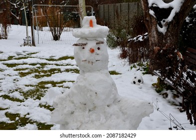 A Snowman Sadly Slowly Melting, Dirty From Mud And Lack Of Snow Will Evoke A Feeling Of Ruin And Ugly Changeable Weather Of Winter February. Frozen Snow On Lawn