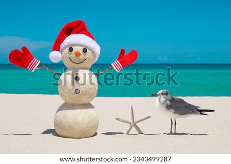Snowman. Sandy Snowman on the beach. Christmas snowman with red Santa Claus hat and mittens. Smiley Snow man. Miami Beach Florida. Winter Holidays. Celebration Happy New Year. Xmas postcards. Travels