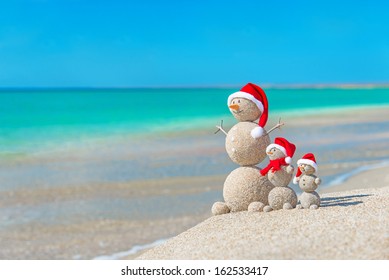 Snowmen family at sea beach in santa hats. New years and christmas holiday in hot countries concept. - Powered by Shutterstock