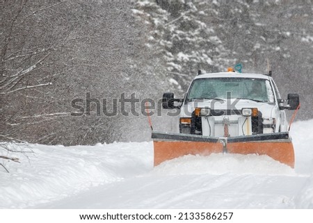 A snowplow clearing a rural road in Ontario during a winter storm