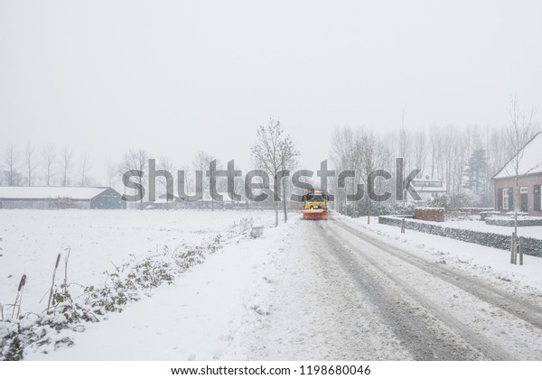 Snowplow removes snow\
off icy road in winter