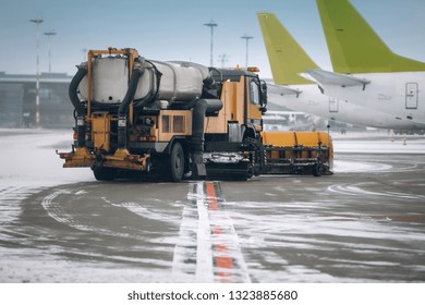 Snowplow removing snow from runways and roads in airport during snow storm