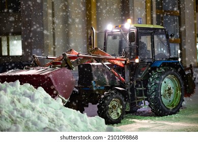 Snowplow Truck, Tractor  Removing Snow On The Road Street In Blizzard Snowstorm At Night. Snow Removal Service Operating In Winter . 