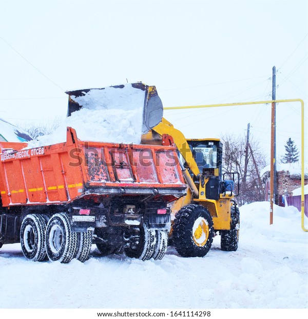Snowplows clean roads from snow in\
winter. Loader and truck work on the road in the private\
sector.