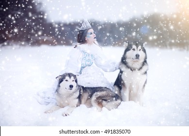 Snow-queen. Fairy tale girl with Huskies or Malamute. Beautiful snow queen witn dogs. Christmas.