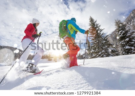 Snowshoe walkers running in powder snow with beautiful sunrise light. Outdoor winter activity and healthy lifestyle