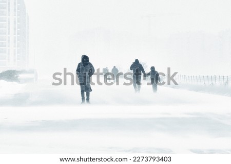 A snowstorm in the city. People are walking down the street during a snowstorm. Strong wind and snowfall. Arctic climate.