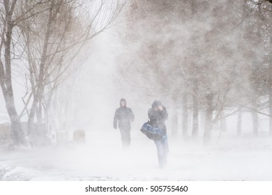 Snowstorm and strong wind in city Nothing visible Silhouettes of two men Blurred image
