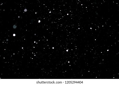 Snowstorm texture. Bokeh lights on black background, shot of flying snowflakes in the air