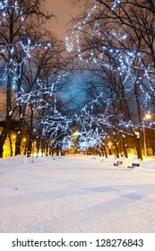 Snowy Avenue With Christmas Lights On Trees In The Evening