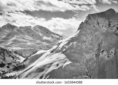 Snowy B&W mountain top with cloudy sky in the background