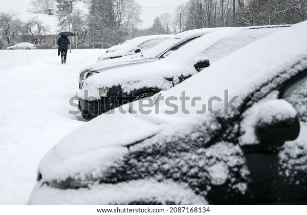 Snowy cars in the parking lot and sidewalk covered\
In Snow.