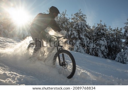 Snowy descent with a mountain bike. Snow downhill with bike, mtb action in winter, with deep snow and sun as a backlight.