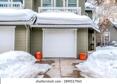 Snowy Driveway And Yard In Winter In Front Of Attached Two Car Garage Of Home