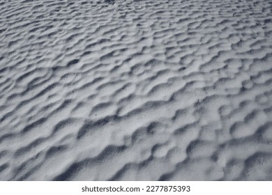 A snowy field with waves formed by the wind in the early spring morning - Shutterstock ID 2277875393