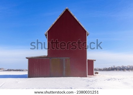 Snowy fields with a red barn in the countryside