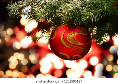 Snowy fir tree branch with red christmas ball and festive lights on the Christmas background with sparkles. Xmas background