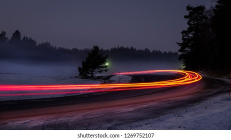 Snowy Foggy Forest Road With Car Tail Lights. Long Exposure.