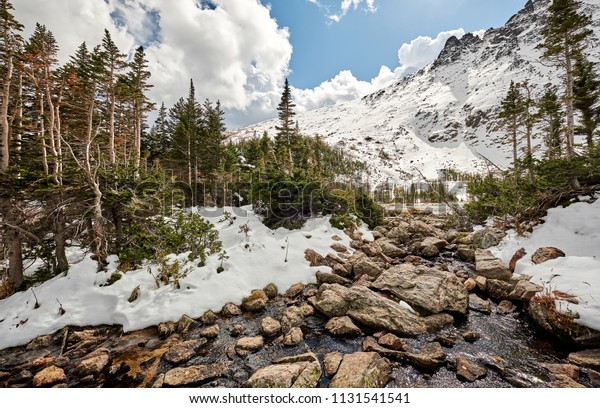 Snowy landscape with rocks and mountains in snow around
at autumn with cloudy sky. Rocky Mountain National Park in
Colorado, USA. 
