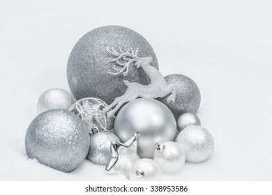 Snowy matt and shiny decorative Christmas ornaments with animal Santa Claus's reindeer at ground level outdoor