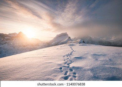Snowy mountain ridge with footprint in blizzard at sunrise