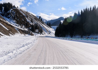 Snowy mountain road winding between snow-covered slopes and pine forests under a clear blue sky. - Powered by Shutterstock