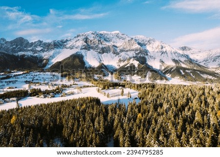 A snowy mountain valley below the Austrian Dachstein glacier. Autumn colours of trees and first snow with blue sky and sun.
