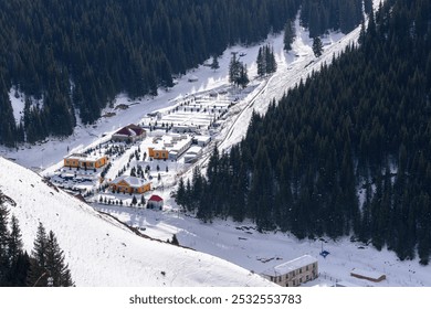 Snowy mountain village with vibrant buildings nestled among dense pine forests, featuring a winding road and a serene winter landscape. - Powered by Shutterstock