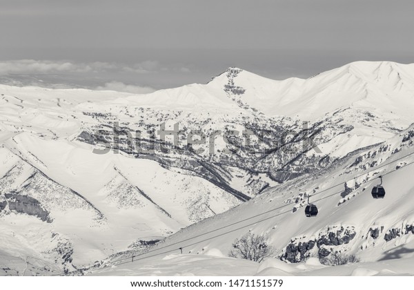 Snowy mountains and gondola lift at ski\
resort at sunny winter day. Caucasus Mountains, Shahdagh,\
Azerbaijan. Black and white retro toned\
landscape.