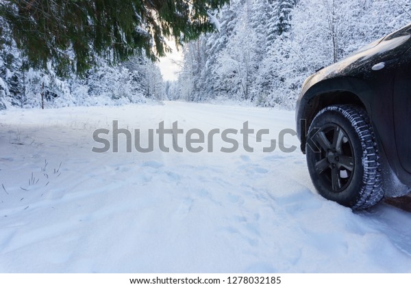 Snowy road in the forest and\
a car