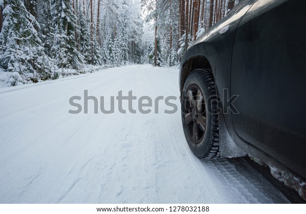 Snowy road in
the forest and the car, side
view