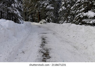 Snowy Road In The Forest With Snowbanks On The Side After Being Snowplowed