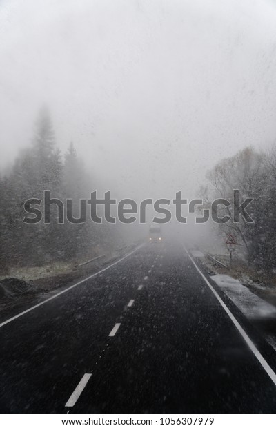 Snowy\
road, on the sides of trees, heavy snow. The concept of the\
problems of the road situation of transportation, transportation,\
increased risk, cleaning roads, vertical\
photo