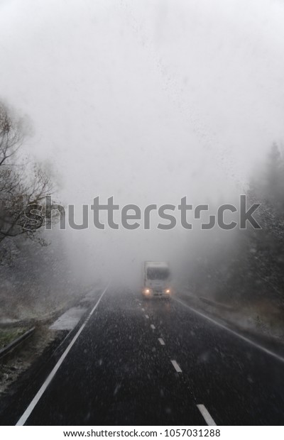 Snowy road, on the sides of trees, heavy snow.\
The concept of the problems of the road situation of\
transportation, transportation, increased risk, cleaning roads. on\
the road truck and cars,\
vertical