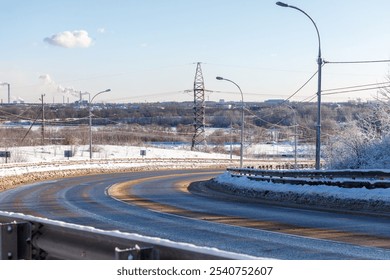 A snowy road with a power line pole in the background. The road is curved and the sky is clear - Powered by Shutterstock