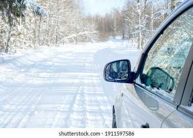 Snowy road. Side of a car with a mirror. Snowy forest in the afternoon 