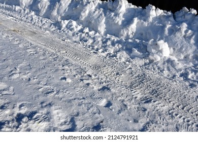 A Snowy Road With Traces Of Shoes And Car Treads. A High Snowdrift On The Side Of The Road