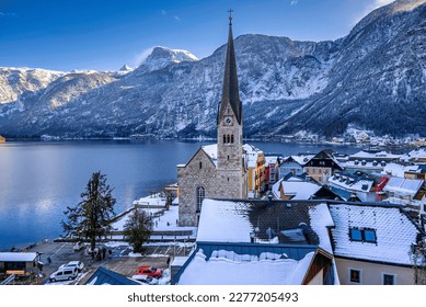 Snowy rooftops of Hallstatt, Austria with the Alpine ranges and the Hallstatt Lake in the background.